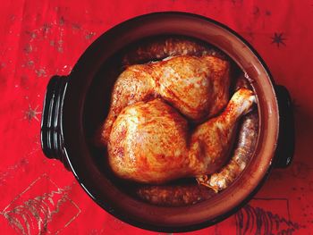 Directly above shot of roasted chicken in container on red tablecloth