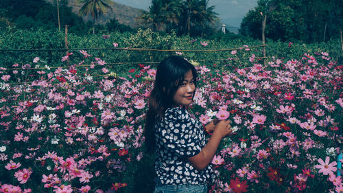 Full length of woman standing by flowering plants