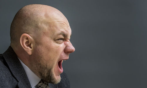 Close-up of frustrated businessman against gray background