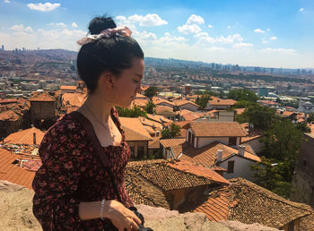 Woman standing by houses against buildings in city