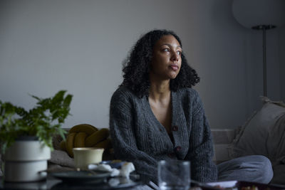 Pensive young woman sitting at home