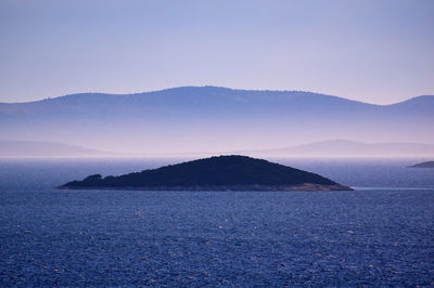 Scenic view of sea and mountains against clear sky