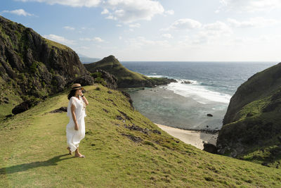 Woman on rock by sea against sky