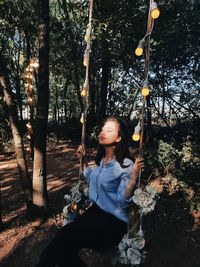 Teenage girl sitting on tree trunk in forest