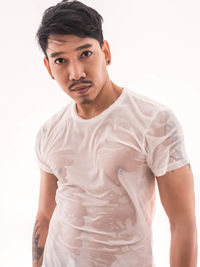 Portrait of young man standing against white background