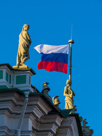 Low angle view of statue against building against clear blue sky