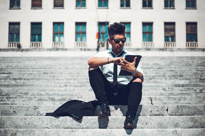 Full length of young man using mobile phone in city