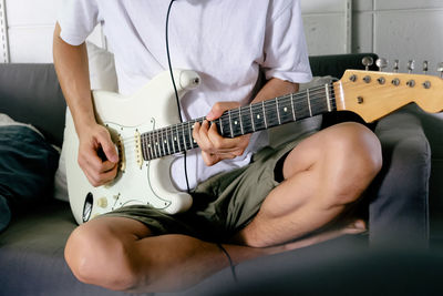 Midsection of man playing guitar