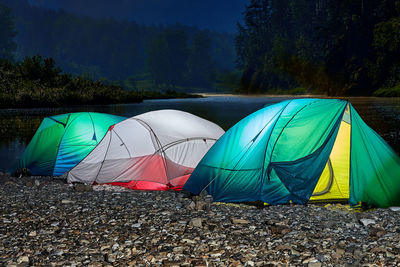 Multi colored umbrellas on field against trees in forest