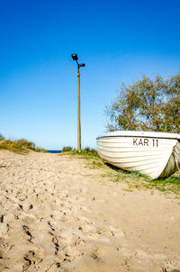 Horse cart on beach against clear blue sky