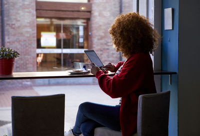 Young woman using digital tablet while sitting at cafe