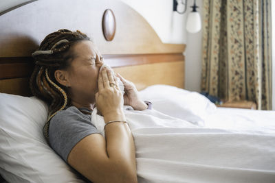 Woman lies in bed with handkerchief pressed to her nose