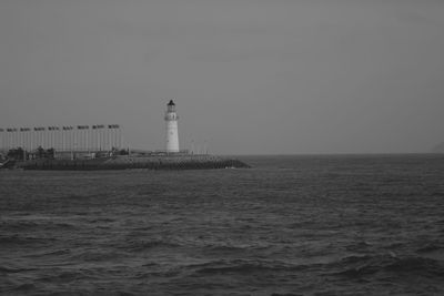 Lighthouse by sea against clear sky