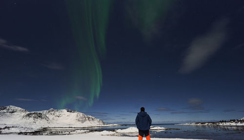 Man standing on snow watching aurora