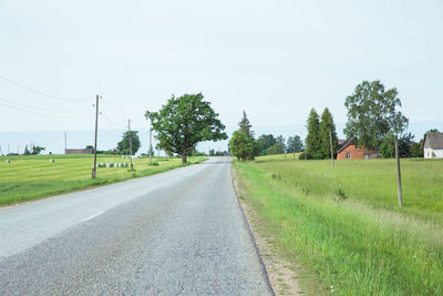 Road amidst trees on field against sky