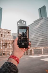 Midsection of woman photographing with mobile phone in city