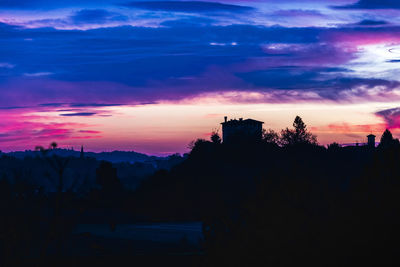 Silhouette trees and buildings against sky during sunset