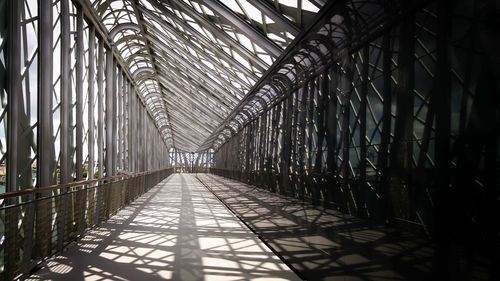 Empty footbridge in city during sunny day