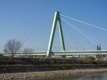 Low angle view of bridge over river against clear blue sky