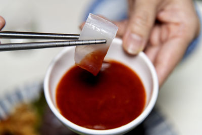 Cropped hand of woman holding squid sashimi 