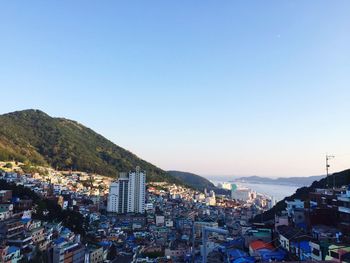 Cityscape by sea against clear blue sky