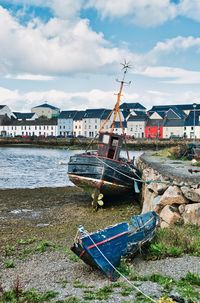 Boat moored on beach against sky