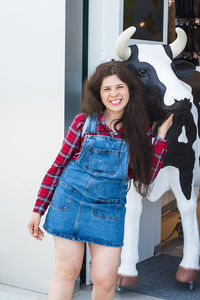 Portrait of smiling young woman standing against wall