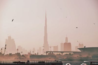 Birds flying over bay against dubai skyline