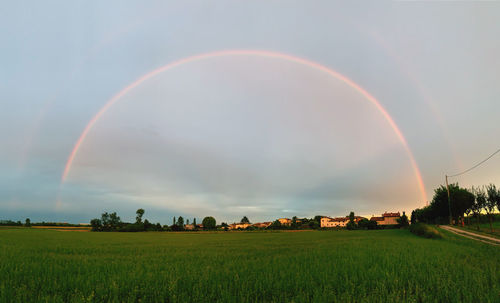 Scenic view of rainbow over field against sky