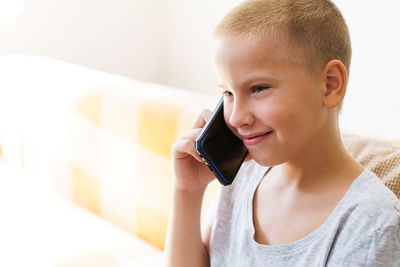 Happy boy talking on the phone while sitting on the couch at home in casual