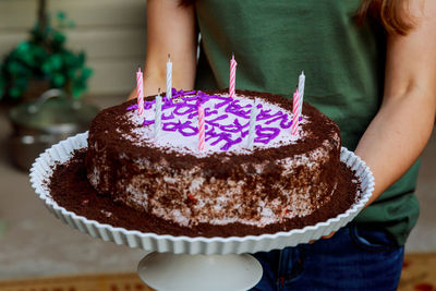 Midsection of woman holding birthday cake while standing at home