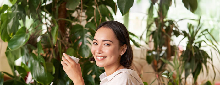 Young woman looking away against plants