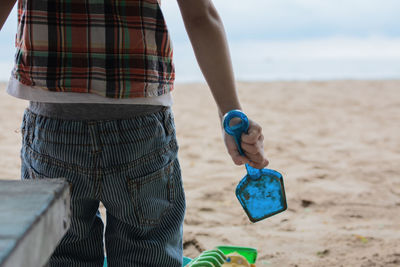 Midsection of boy holding toy while playing at beach