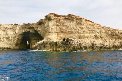 Rock formations by sea against sky