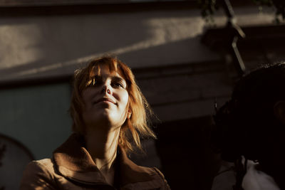 Low angle view of smiling young woman with blond hair in city