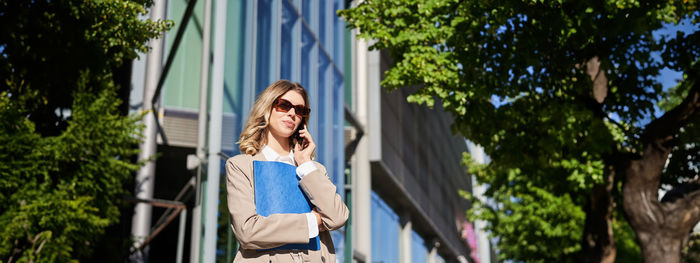 Portrait of young woman standing against trees