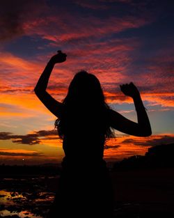 Silhouette woman against cloudy sky during sunset