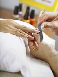 Cropped hands of woman doing manicure of female customer in spa