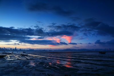 River by city against cloudy sky during sunset