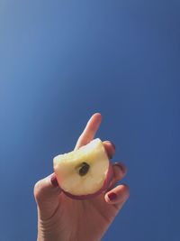 Midsection of person holding ice cream against blue sky