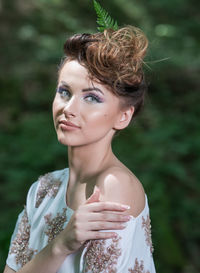 Portrait of young woman standing against plants
