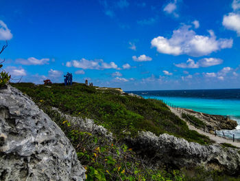 Scenic view of sea by cliff against blue sky