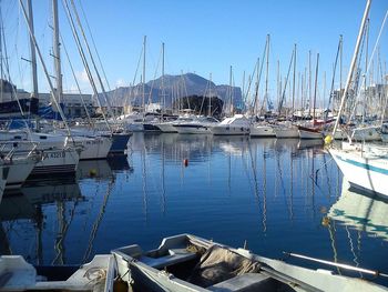 Sailboats moored at harbor against clear sky