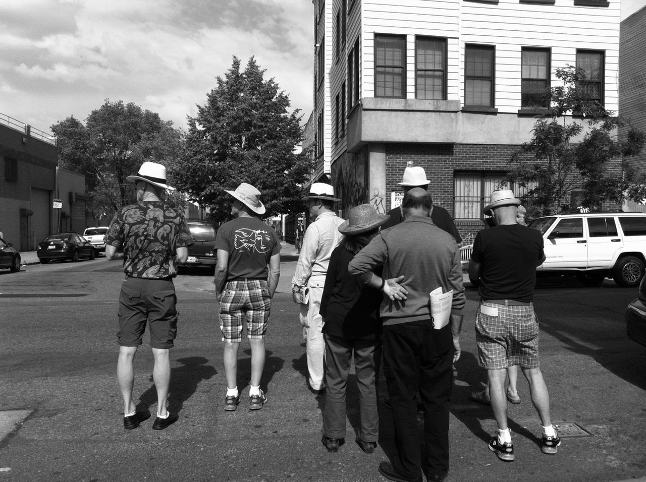 building exterior, street, architecture, city, built structure, men, city life, walking, person, lifestyles, tree, car, transportation, road, land vehicle, city street, leisure activity, day, outdoors