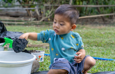 Little child shovels soil into pots to prepare plants. toddler boy digging soil for planting 
