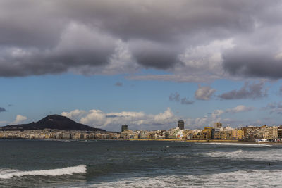 City at waterfront against cloudy sky