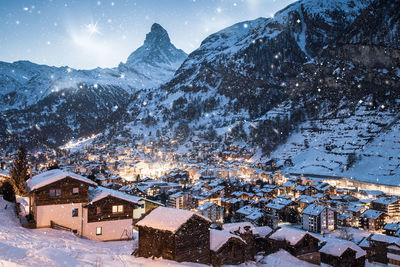 Snow covered houses and mountains against sky