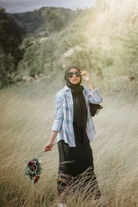 Portrait of young woman standing on field