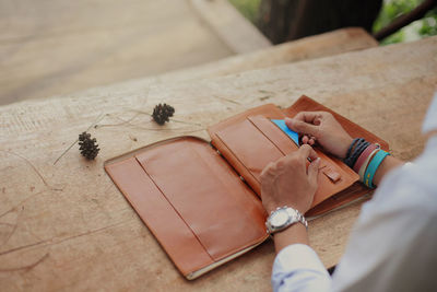 Cropped hands of woman with purse at table