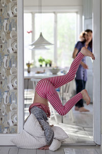 Girl doing headstand, mother in background